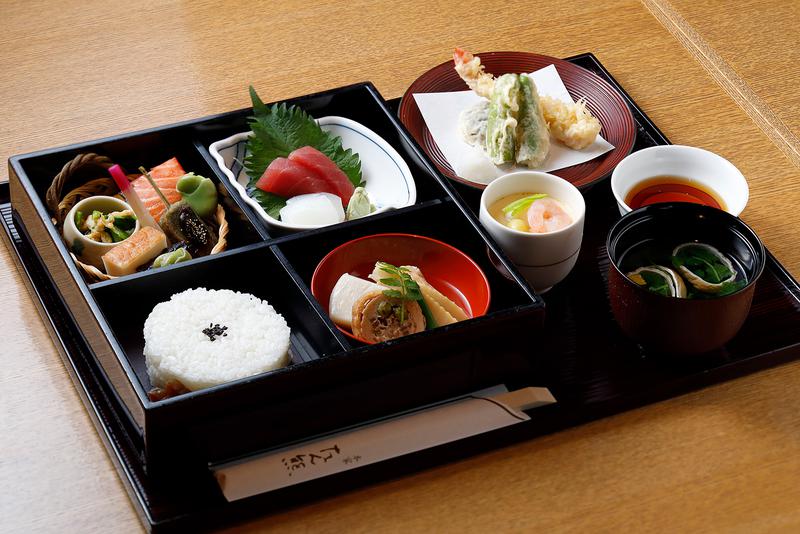 「鴨川弁当」3024円(税込)。松花堂弁当に茶碗蒸し、海老、椎茸、ししとうの天ぷらがプラスされたデラックスなお弁当です。特に煮物は本家たん熊の腕の見せ所。少し甘みがある煮汁の深い味わいをご堪能ください。※内容、食材は季節によって異なります。